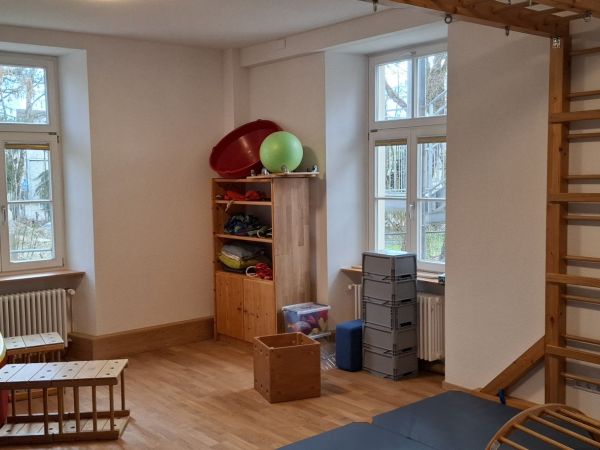 Das Bild zeigt unser Bewegungsraum mit verschiedenen Turnelementen, Gymnastikbällen und einem Klettergerüst.