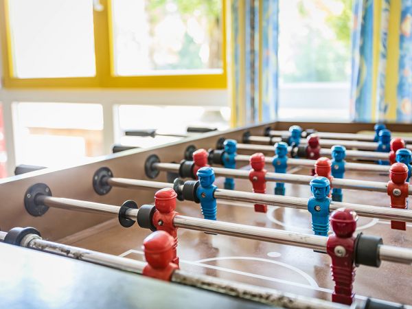 Das Bild zeigt einen Tischkicker mit roten und blauen Spielfiguren.
